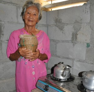 Dolores holding ‘baki’ (bamboo container) used when picking shrimps, snails and shells in the river and her stove purchased out of her stipend.